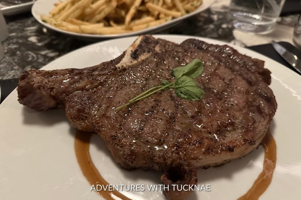 Juicy grilled steak on a white plate, seasoned with herbs, accompanied by a side of golden fries, served in a Las Vegas steakhouse.