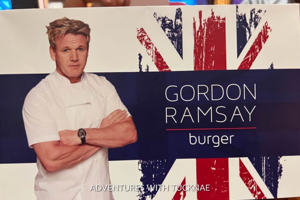 Promotional image of Gordon Ramsay with a stylized UK flag backdrop, advertising the celebrity chef's burger restaurant in Las Vegas.