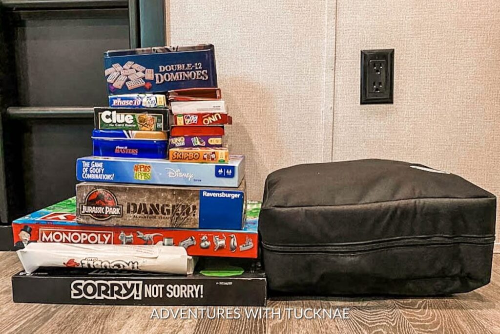 A pile of games sitting on the floor in an RV next to a game organizer