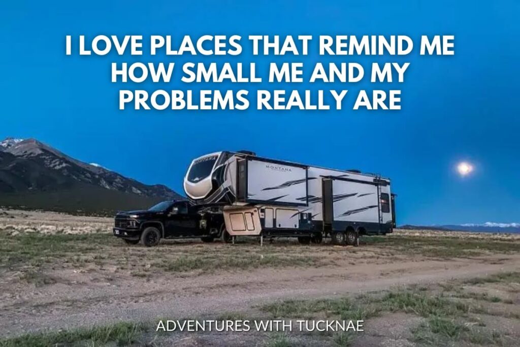 A truck towing an RV parked in a vast desert under a night sky with the quote 'I love places that remind me how small me and my problems really are.'