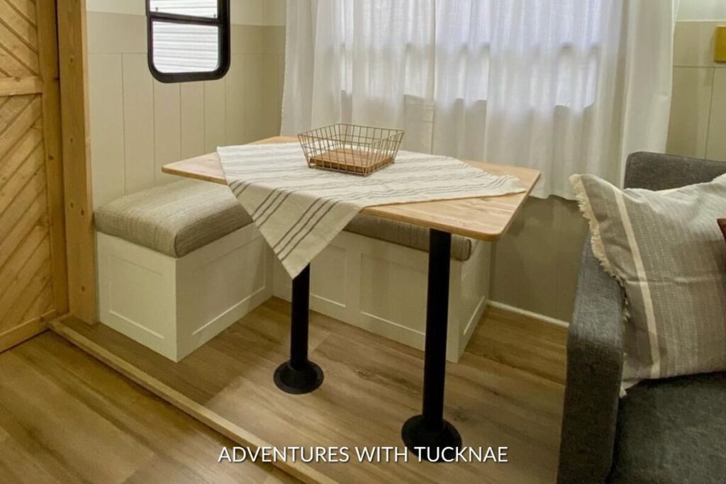 A smart RV dining solution with a compact wooden table and bench storage, optimizing space in a small area.
