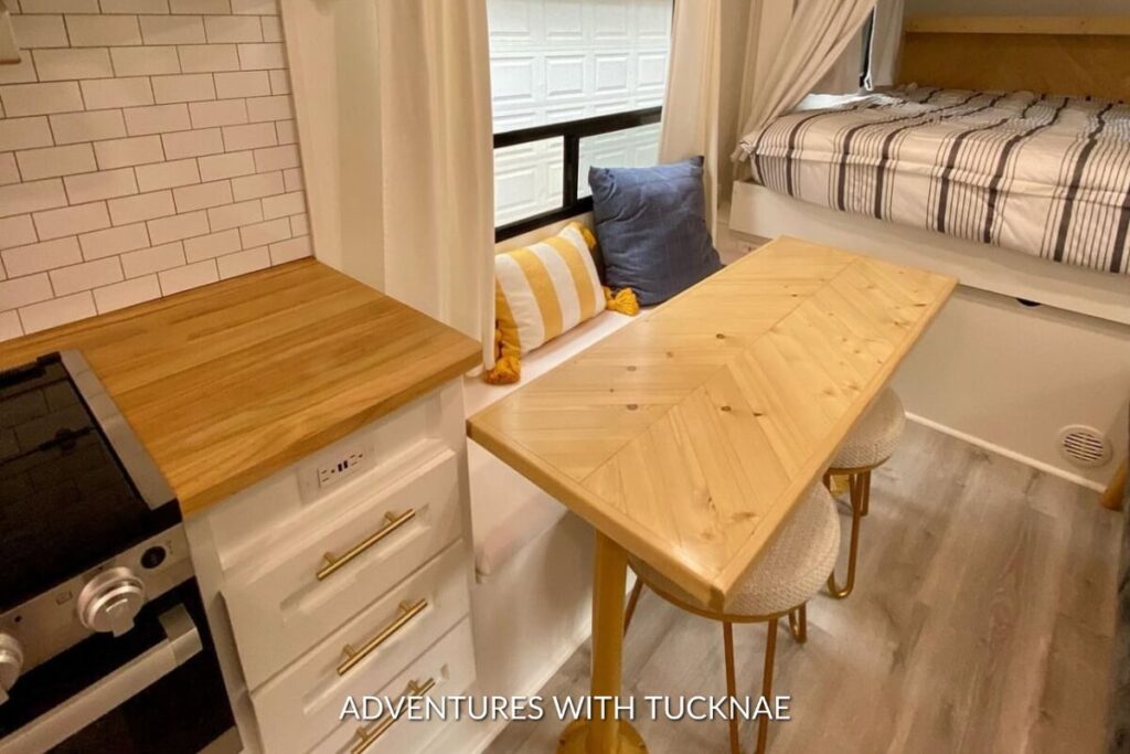 A functional and chic RV dining corner with a wooden extendable table, soft chairs, and elegant décor, maximizing space and style.