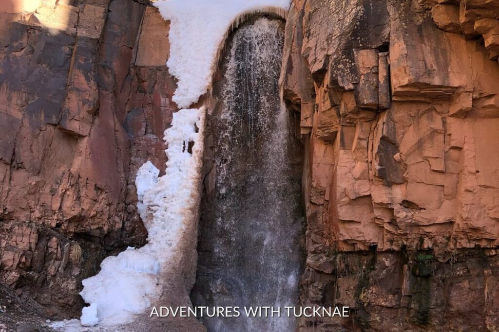 A frozen Hidden Haven Waterfall in Southern Utah, with icicles contrasting against the red rock cliff during winter.