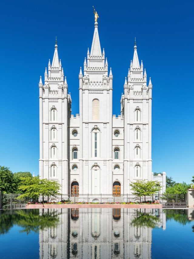 The majestic Salt Lake Temple stands with its striking spires against a dramatic sky, surrounded by manicured grounds, a historic and instagrammable landmark in Utah.