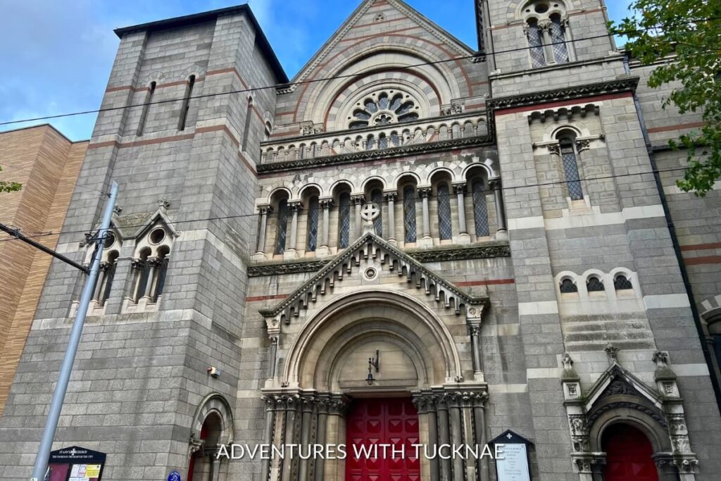 The Romanesque revival architecture of St. Ann’s Church in Dublin, featuring a rose window and ornate stone carvings, perfect for Instagram.