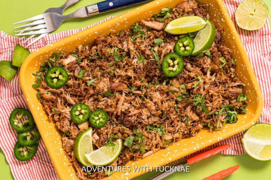 Instant Pot Carnitas: Juicy and flavorful Instant Pot carnitas in a bright yellow serving dish, sprinkled with cilantro and lime wedges, ready for a festive campsite feast.