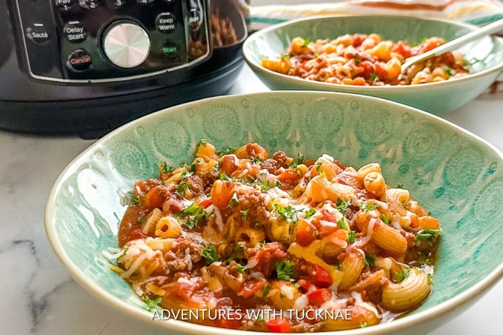A hearty bowl of Instant Pot Chili Cheese Mac with melted cheese and fresh herbs on top, a perfect comfort food for camping meals.