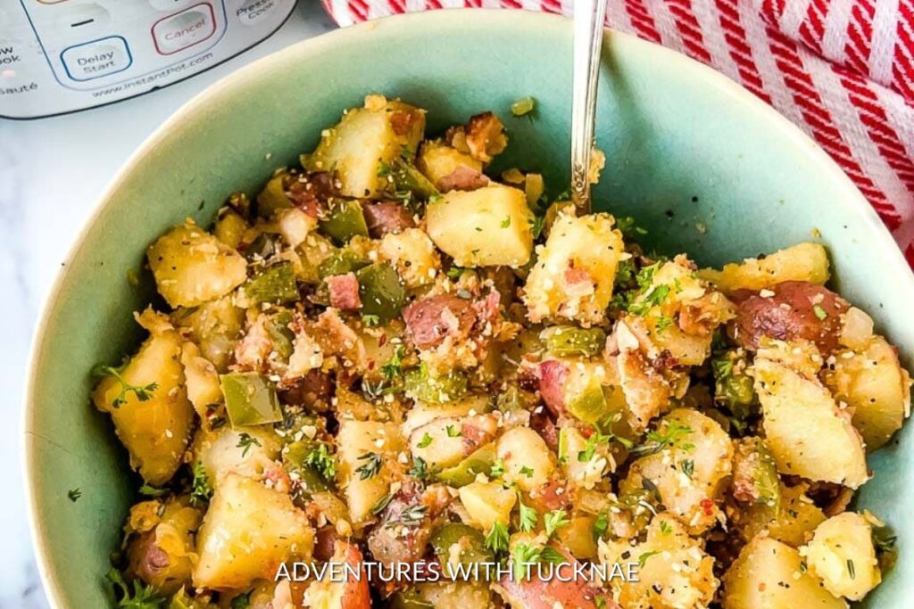 Instant Pot Breakfast Potatoes with diced ham, green peppers, and a sprinkle of herbs, served in a ceramic bowl, ideal for an energizing start on a camping trip.
