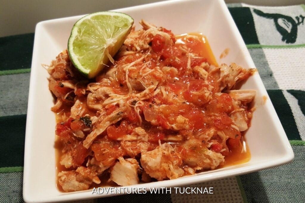 Instant Pot Salsa Lime Chicken: White plate hosting zesty Instant Pot salsa lime chicken, garnished with a lime wedge, for an easy camping dinner.