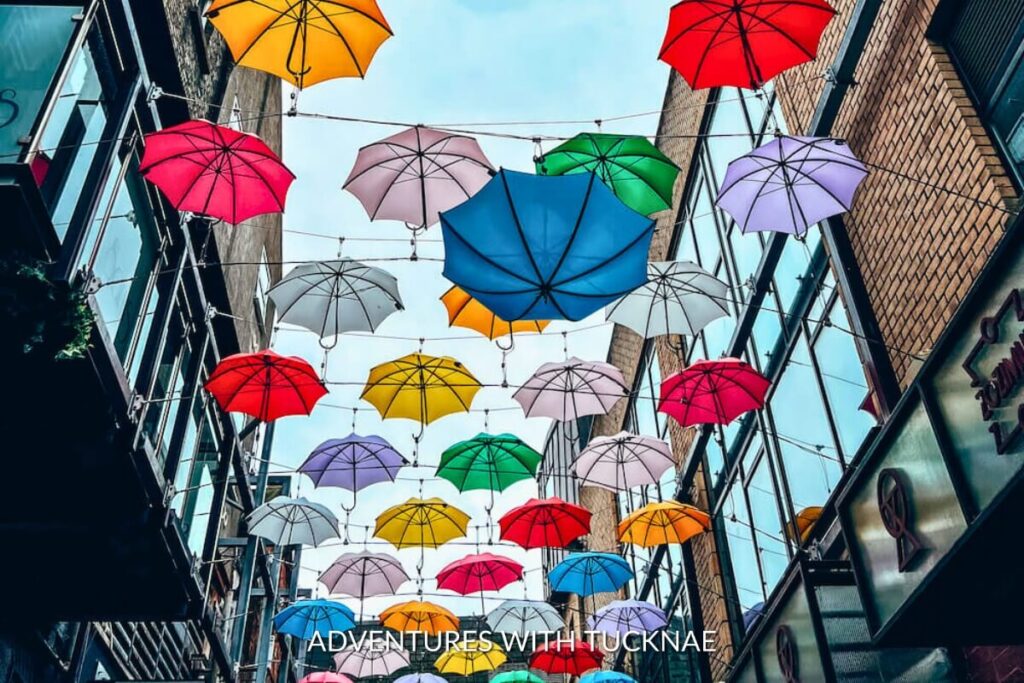 Colorful umbrellas float above a bustling street in Dublin, Ireland, adding a vibrant and playful atmosphere to this Instagrammable urban spot in Ireland.