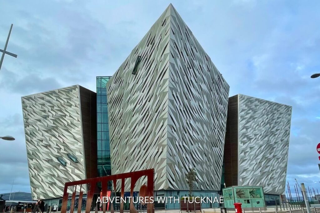 The modern, angular design of the Titanic Belfast museum under a cloudy sky, a must-visit landmark for a cultural weekend break in Ireland.