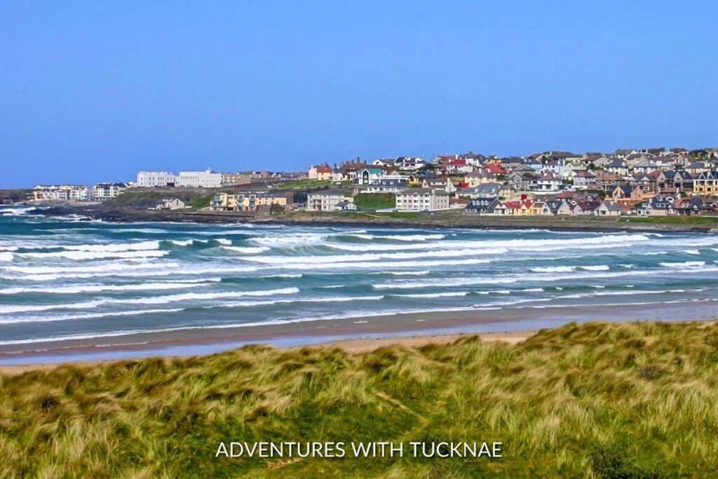 The golden sands and rolling waves of Portstewart Strand, backed by a picturesque town, capturing the essence of coastal weekend breaks in Ireland.