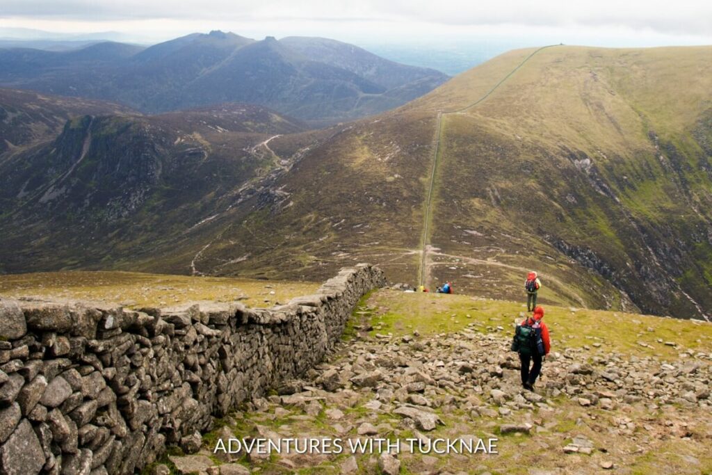 Hikers alongside the stone wall trails of Slieve Donard in Newcastle, offering panoramic views for active weekend breaks in Ireland.