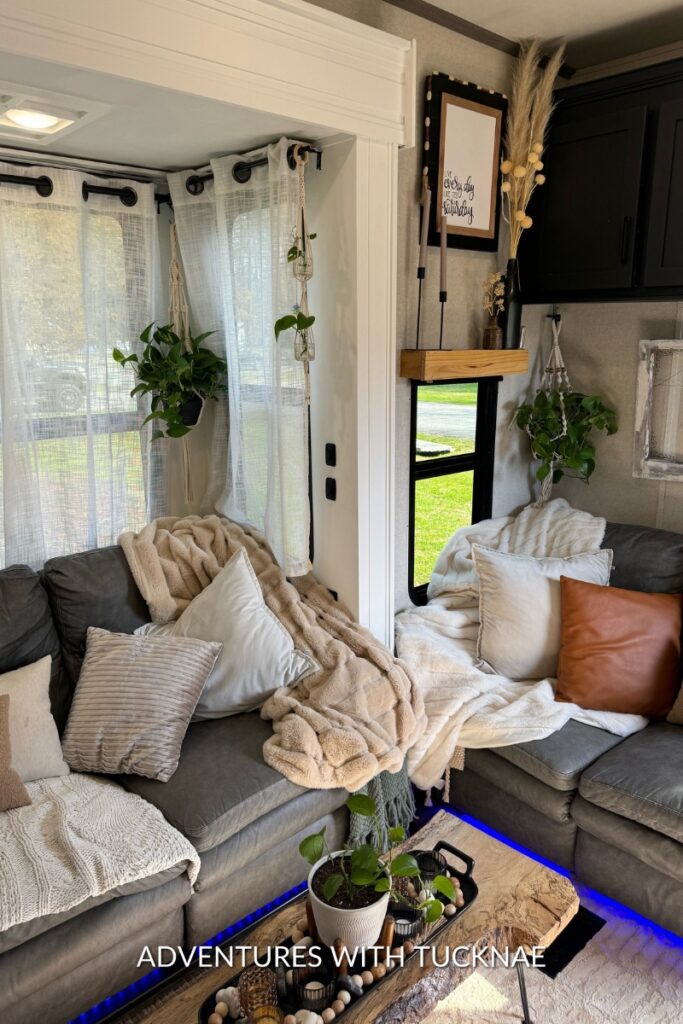 A peaceful RV living space with plush throw blankets and pillows, adorned with hanging potted plants that bring a burst of greenery and freshness into the comfortable lounge area.