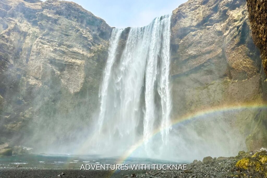 The majestic Skogafoss waterfall in Iceland with a rainbow formed in the mist at the base of the falls. 