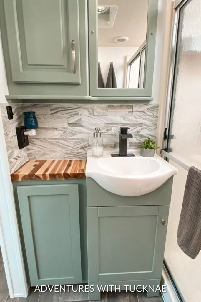 An RV bathroom renovation with new countertops and green painted cabinets