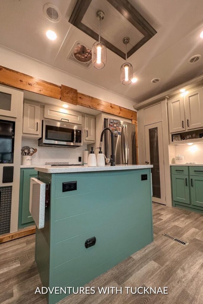 A renovated RV kitchen with grey and green painted cabinets and new slide trim