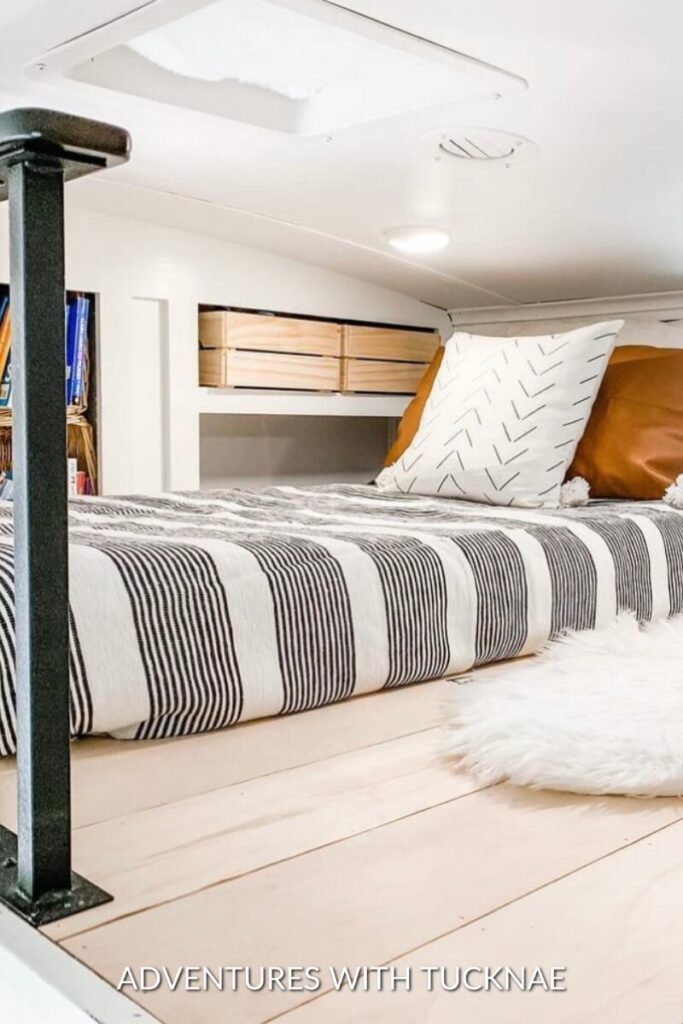 An RV loft renovated in a cute style with pillows and a rug