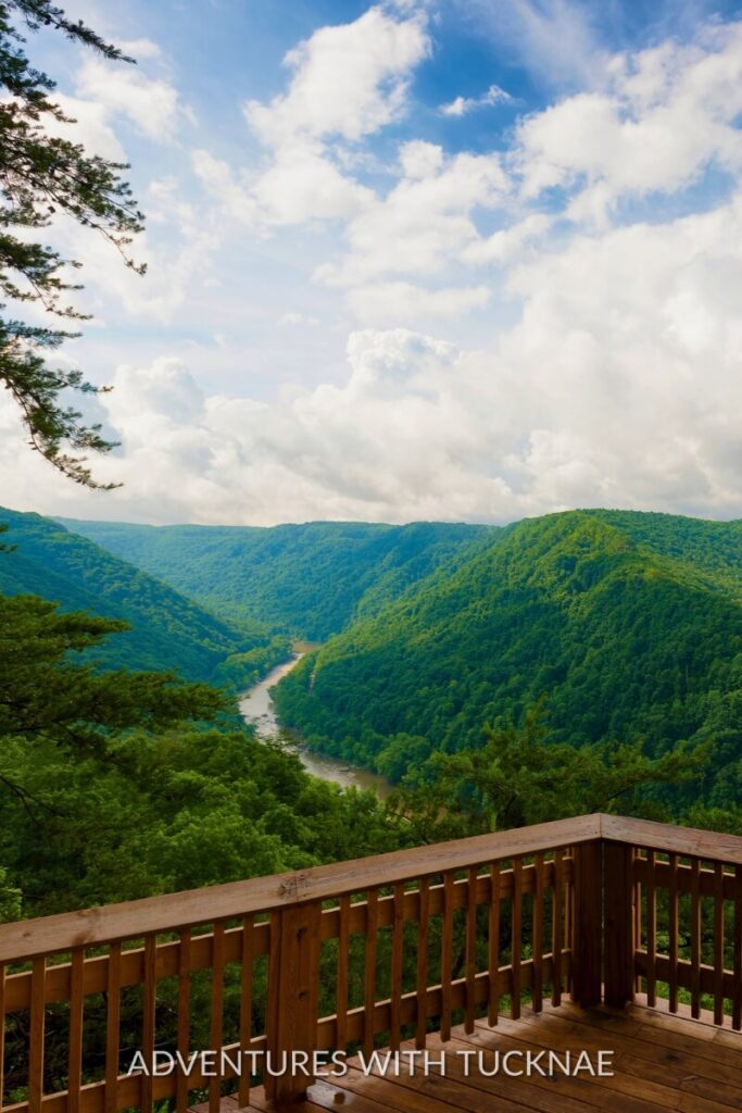 A scenic overlook with a wooden deck and a river winding through green hills at New River Gorge National Park.