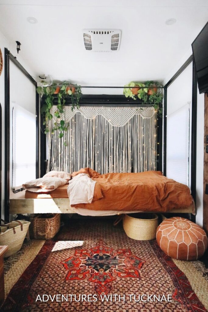 Bohemian-style RV bedroom renovation with macrame hangings, plants, and orange bedding