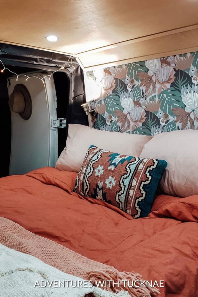 A tiny van bedroom with colorful bedding and wallpaper