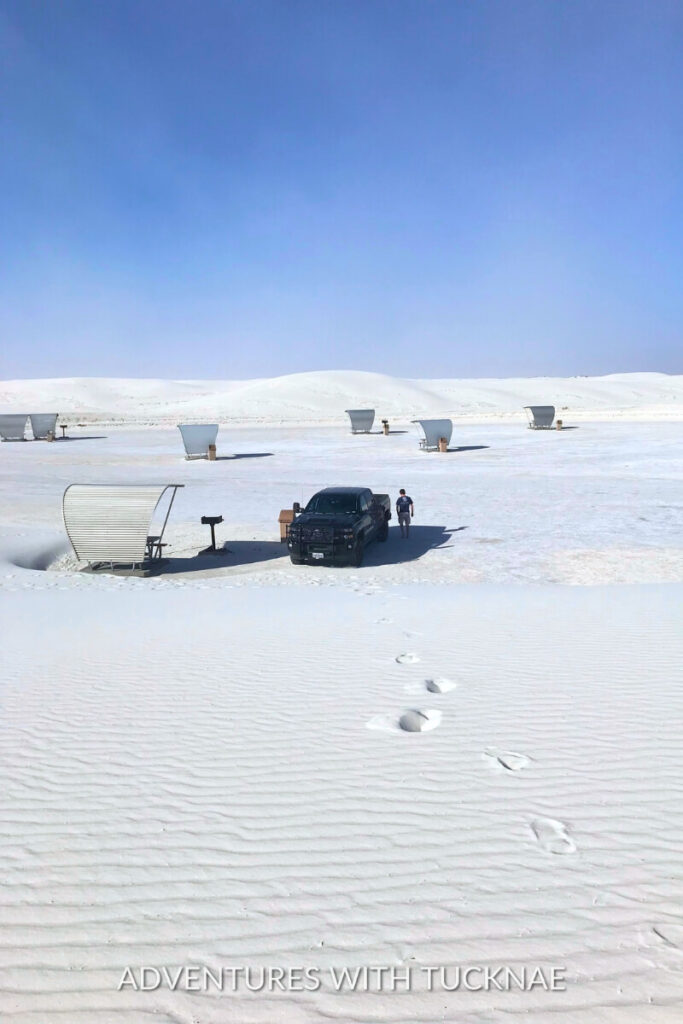 A black truck parked on the white gypsum dunes under a clear blue sky at White Sands National Park.